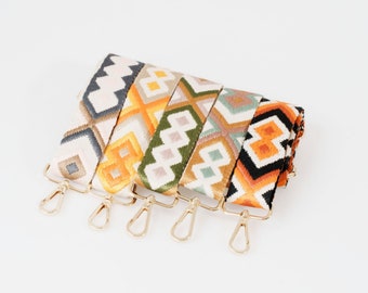 May include: Five colorful woven straps with geometric patterns in shades of orange, yellow, green, black, and white. Each strap has a gold metal hook.