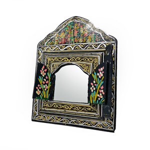 May include: A decorative black framed mirror with a rectangular shape and an arched top. The frame is adorned with gold, silver, and black patterns. The top features a colorful painted scene, and the sides have floral accents.