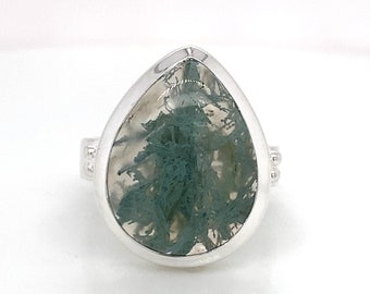 May include: A silver ring with a teardrop-shaped green moss agate stone.