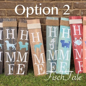 Op de afbeelding: Optie 2 van een set houten borden met het woord "HOME" in wit op elk bord. Elk bord heeft een ander ontwerp, waaronder een teckel, een zeemeermin, een krab en een varken. De borden zijn in verschillende kleuren geschilderd, waaronder blauw, rood en bruin.