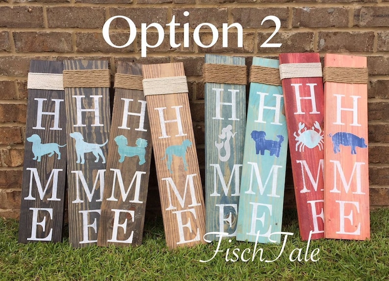 Op de afbeelding: Optie 2 van een set houten borden met het woord "HOME" in wit op elk bord. Elk bord heeft een ander ontwerp, waaronder een teckel, een zeemeermin, een krab en een varken. De borden zijn in verschillende kleuren geschilderd, waaronder blauw, rood en bruin.