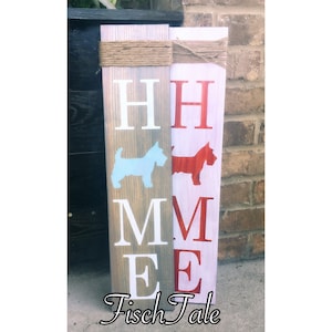 May include: A wooden sign with the word "HOME" spelled out in white letters. The sign is divided into two sections, with a blue silhouette of a dog on the left side and a red silhouette of a dog on the right side. The sign is decorated with twine and the words "Fisch Tale" are written at the bottom.