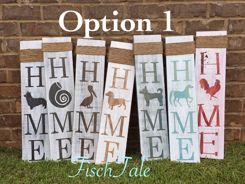 Op de afbeelding: Zes houten borden met het woord "HOME" gespeld in verschillende kleuren en lettertypen. Elk bord heeft een ander silhouetbeeld, waaronder een hond, een paard, een haan, een schelp, een pelikaan en een corgi.