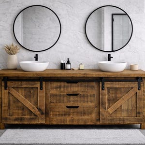 May include: A rustic wooden bathroom vanity with two white vessel sinks and black faucets. Two round black mirrors hang above the sinks. The vanity has a distressed finish and barn door style cabinet doors.