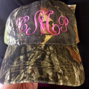May include: Camouflage baseball cap with a pink embroidered monogram "E M P".