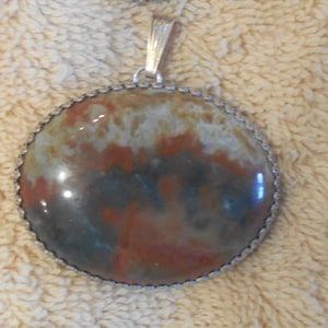 May include: A silver pendant with a round, brown, gray, and white agate stone.