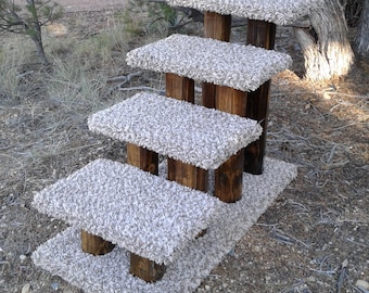 May include: A multi-level cat tree with four platforms covered in light beige carpet. The platforms are supported by dark brown wooden posts, creating a tiered structure for feline climbing and lounging. The cat tree is designed for indoor use.