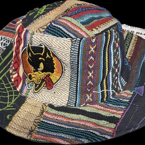 May include: A multi-colored patchwork bucket hat with a cartoon wolf patch. The hat is made of different fabrics and has a unique, bohemian style.