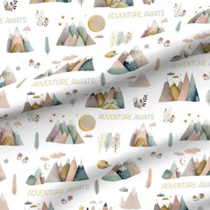 May include: White fabric with a repeating pattern of watercolor mountains, clouds, stars, moons, and trees. The mountains are in shades of pink, blue, green, and brown. The text 'Adventure Awaits' is repeated throughout the pattern in a gold color.