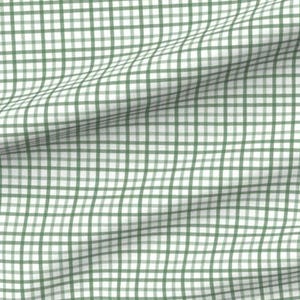 May include: A fabric with a green and white plaid pattern. The design features a grid of intersecting lines, creating a classic checkered appearance. The fabric is slightly wrinkled, adding texture to the design.