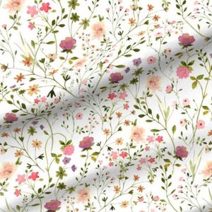 May include: A fabric with a white background featuring a watercolor floral pattern. The design includes pink, purple, and peach-colored flowers, along with green leaves and stems. The pattern is a repeating design.