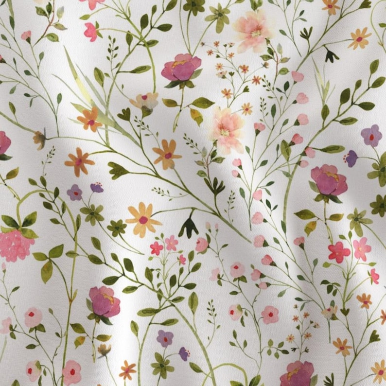 May include: A white fabric with a watercolor floral pattern. The design features a variety of flowers in shades of pink, purple, orange, and yellow, along with green leaves and stems. The flowers are scattered across the fabric.