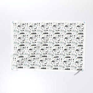 May include: White fabric with a repeating pattern of stylized mountains, trees, clouds, and suns in shades of gray, blue, and green. The design is a whimsical illustration of a mountain landscape.