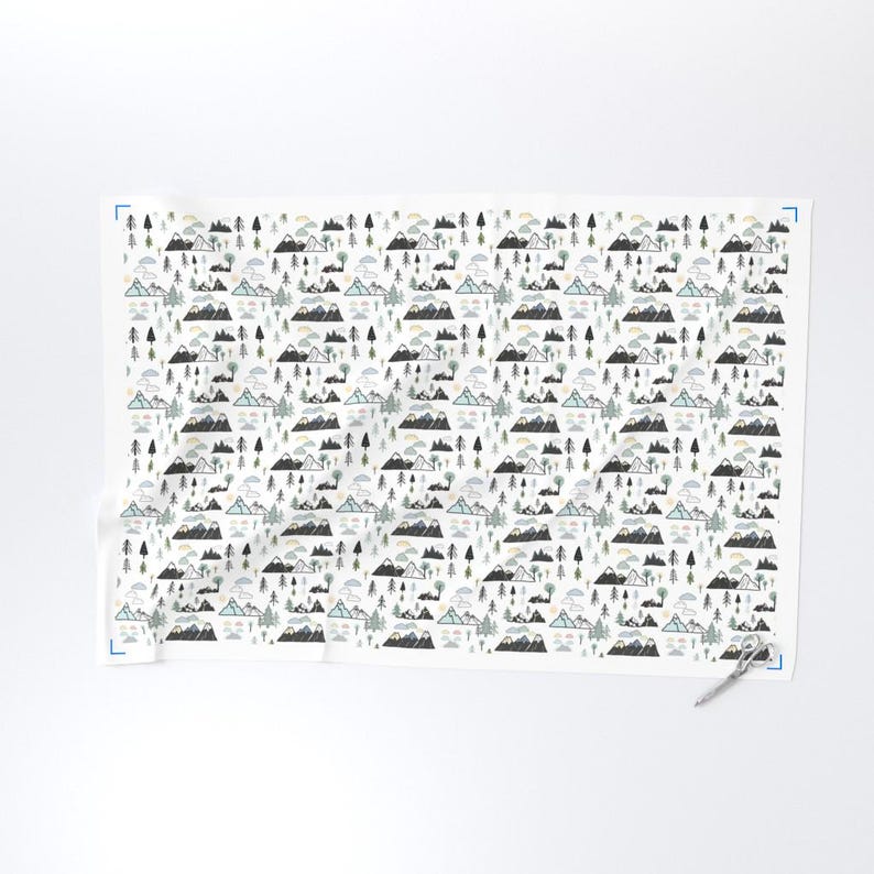 May include: White fabric with a repeating pattern of stylized mountains, trees, clouds, and suns in shades of gray, blue, and green. The design is a whimsical illustration of a mountain landscape.
