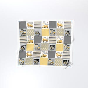 May include: A white and yellow patchwork design featuring construction vehicles, including cement mixers and dump trucks. The design includes the words "Build Your Dreams", "Work Hard", "Dirt and Rocks", and "Stay Humble".