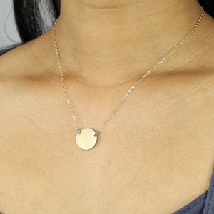 Puede incluir: Un collar de cadena de oro con un colgante redondo de oro liso.