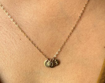 May include: A gold chain necklace with three small gold discs, each with a different letter engraved on it.