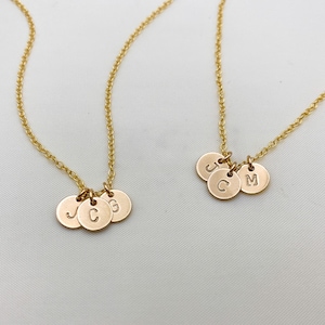 May include: Two gold necklaces with initial charms. One necklace has three charms with the letters J, C, and G. The other necklace has two charms with the letters J and M.
