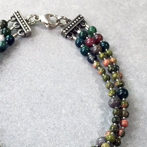 Three strands of colorful and two sizes of Jasper Rounds are spaced with gray Seeds Beads, with Bali Silver 3-strand detailed End Pieces