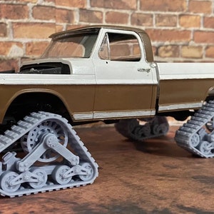 May include: A white and brown pickup truck with grey tracks. The truck is a model and has a detailed interior.