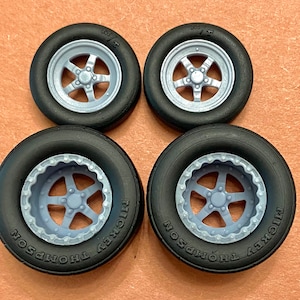 May include: Four black rubber tires with silver rims and a five-spoke design. The tires have the words "Mickey Thompson" printed on the side.