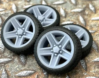 May include: Four gray, five-spoke, car wheels with black tires. The wheels are made of a smooth, hard plastic and have a realistic look.