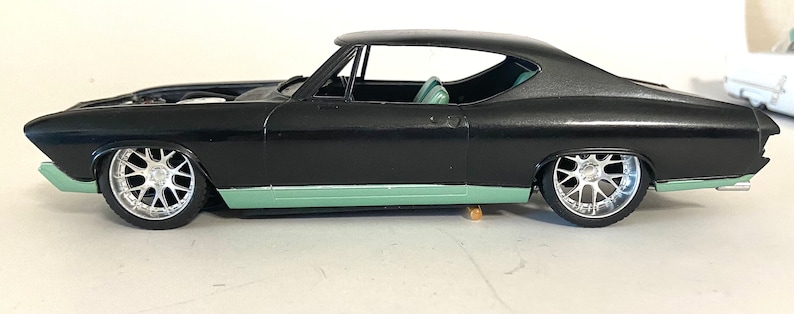 Puede incluir: Modelo de coche negro con moldura verde y ruedas plateadas. El coche es un Chevrolet Chevelle de 1967.