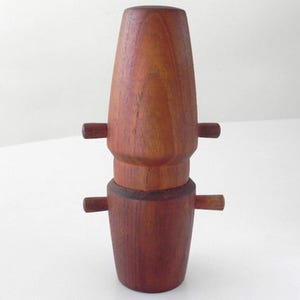 Może przedstawiać: Drewniany zestaw solniczki i pieprzniczki o cylindrycznym kształcie. Solniczki wykonane są z ciemnobrązowego drewna i mają małe uchwyty po bokach.