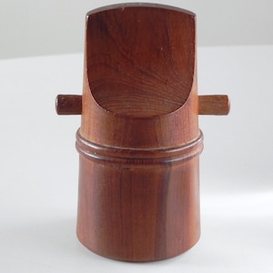 Może przedstawiać: Drewniany zestaw solniczki i pieprzniczki o unikalnym designie. Solniczki wykonane są z ciemnobrązowego drewna i mają cylindryczny kształt z zaokrąglonym wierzchołkiem. Górna część każdej solniczki ma mały, okrągły otwór do wsypywania soli lub pieprzu.