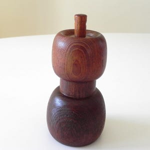 Może przedstawiać: Drewniany zestaw solniczki i pieprzniczki z ciemnobrązowym wykończeniem. Solniczki są okrągłe i mają cylindryczny wierzchołek.