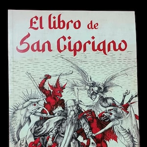 May include: A vintage book titled "El libro de San Cipriano" with a detailed illustration. The cover features a central figure surrounded by red demons and winged creatures, with text in red. The book has a white background.