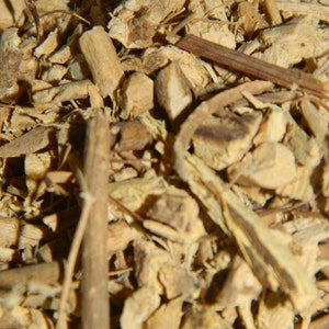 May include: Close-up of a pile of dried, light brown, and tan root bark. The bark is broken into small pieces and has a rough texture.