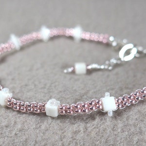 May include: A delicate bracelet featuring rose gold beads and white square accents. The bracelet has a silver clasp and is approximately 17.78 cm long, perfect for everyday wear or special occasions.