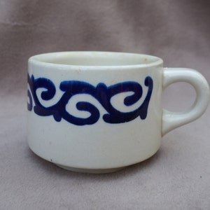May include: White ceramic mug with a blue and white swirling design around the rim.