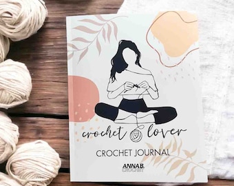 May include: A white crochet journal with a black and white illustration of a person crocheting. The journal has the text "crochet lover" and "CROCHET JOURNAL" on the front. The journal also has the text "ANNAB. CROCHET" on the front.