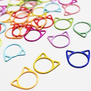 May include: A collection of colorful cat-shaped metal rings. The rings are in various colors, including blue, green, yellow, orange, pink, and purple.