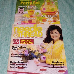May include: Two magazines are stacked on top of each other. The top magazine is titled "Today's Creative Homearts" with "Summer Party Set" on the cover. The bottom magazine is "Needle & Thread" with "Over Spring 30 Designs!" on the cover.