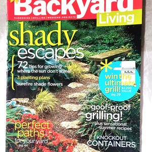 Puede incluir: Una portada de revista para "Backyard Living" con el título "Shady Escapes". La portada presenta un camino de jardín, plantas y el texto "perfect paths for your yard". También promociona la parrilla y la jardinería en contenedores.