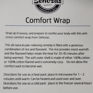 May include: A white comfort wrap with the text "Comfort Wrap" and "Sehosas" printed on it. The wrap is filled with rice and flaxseed and can be used as a heat or cold pack. The text on the wrap also includes directions for use as a heat pack and a cold pack.