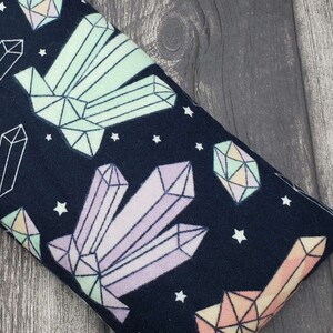 May include: A dark blue fabric eye pillow with a repeating pattern of pastel coloured crystals and white stars.