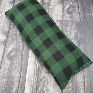 May include: A green and black plaid fabric eye pillow. The pillow is rectangular and has a seam around the edges.