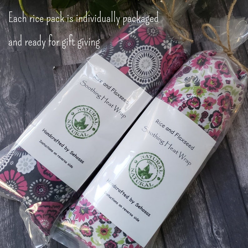 May include: Two individually packaged rice and flaxseed soothing heat wraps. The wraps are handmade and feature a floral print fabric. The packaging includes the text "Rice and Flaxseed Soothing Heat Wrap" and "Handcrafted by Sehosas".