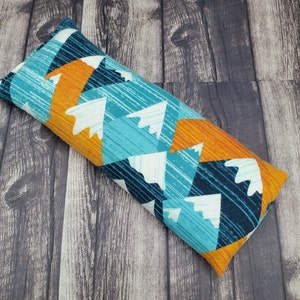 May include: A blue, orange, and white patterned fabric eye pillow. The pillow is rectangular and has a geometric design.