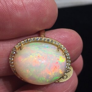 Op de afbeelding: Een gouden ring met een grote ovale opaal-edelsteen omringd door een halo van kleine diamanten.