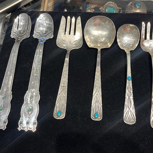 May include: Set of six silver serving utensils with turquoise accents. The set includes two spoons, two forks, and two serving spoons.