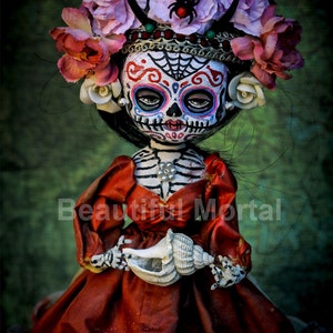 May include: A Day of the Dead doll with a sugar skull face wearing a red dress and a flower crown. The doll is holding a seashell.