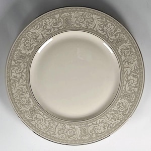 May include: A white ceramic dinner plate with a silver-grey floral pattern around the edge.
