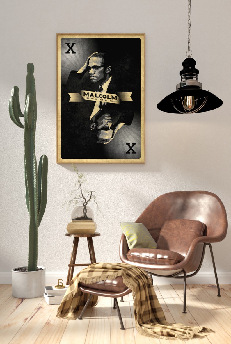 May include: A black and white poster with a portrait of Malcolm X. The poster is framed in a light wood frame and has the text "Malcolm X Our Black Guiding Prince" and an "X" in each corner.