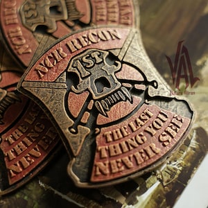 May include: A shield-shaped patch featuring a skull with fangs, crossed rifles, and the text NCR RECON 1ST THE LAST THING YOU NEVER SEE. The design has a weathered bronze and dark red finish with raised lettering and a textured, metallic appearance.