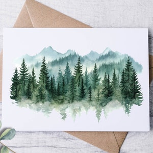 May include: Watercolor art print of a forest scene with evergreen trees and mountains in shades of green and blue. The artwork is on a white card, with a brown envelope behind it. Eucalyptus leaves are in the foreground.
